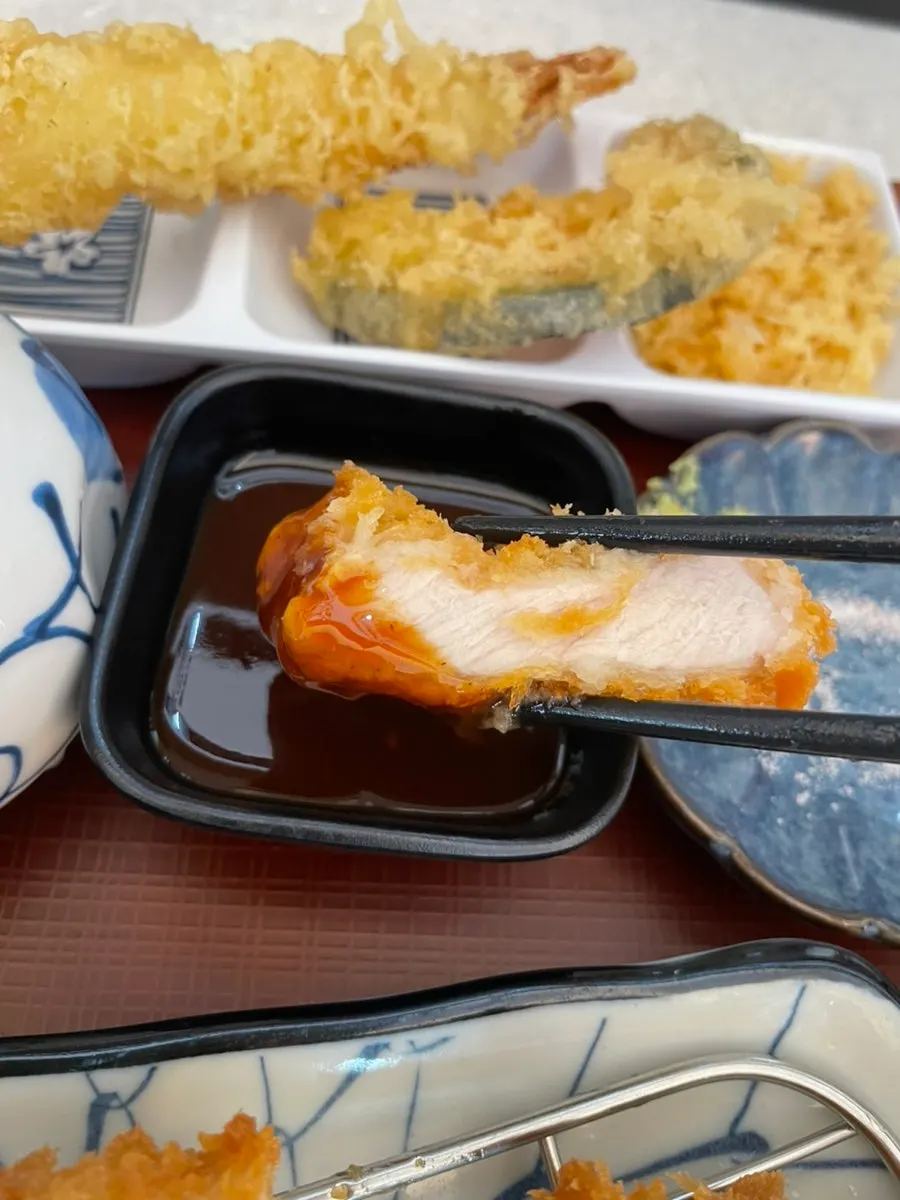 A piece of tonkatsu picked up with chopsticks