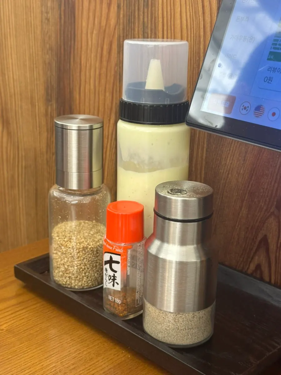 Sesame, pepper, and salad dressing set on the table