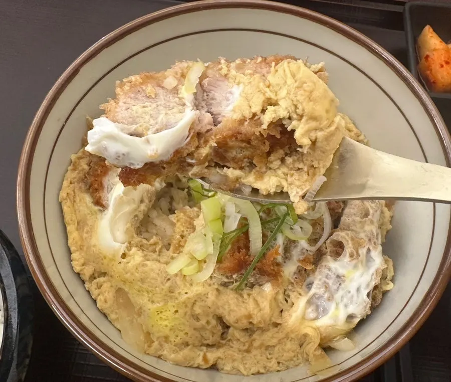 A spoonful of katsudon with rice, egg, and pork cutlet together