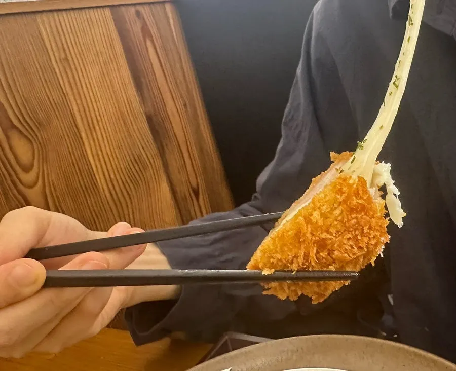 Lifting the cheese katsu with cheese stretching out