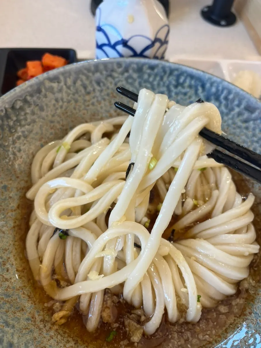 Chewy udon noodles lifted with chopsticks