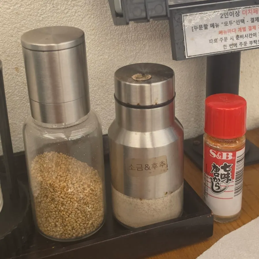 Sesame grinder, salt and pepper, and hot sauce on the table