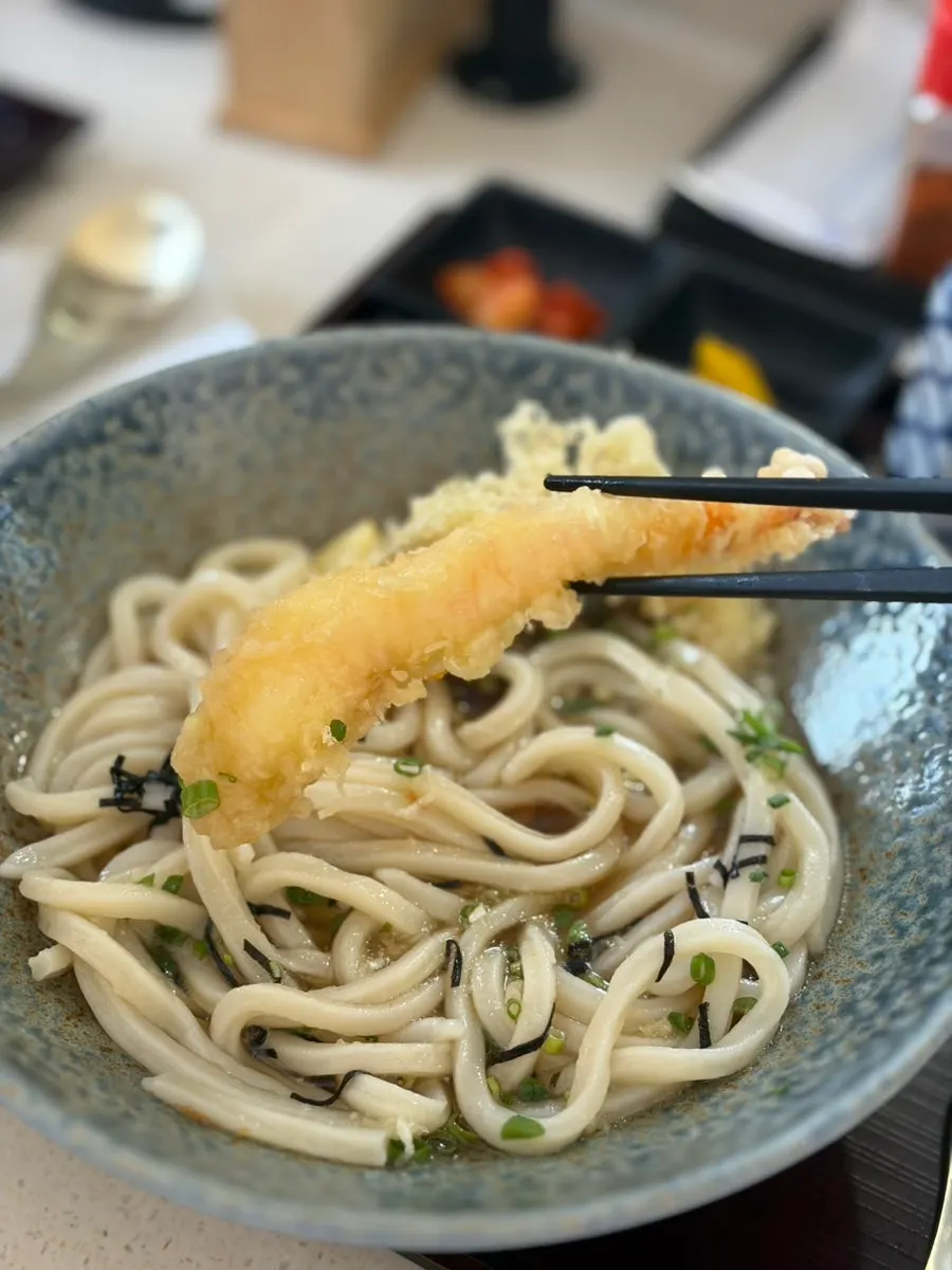 Chewy house-made udon noodles being lifted up