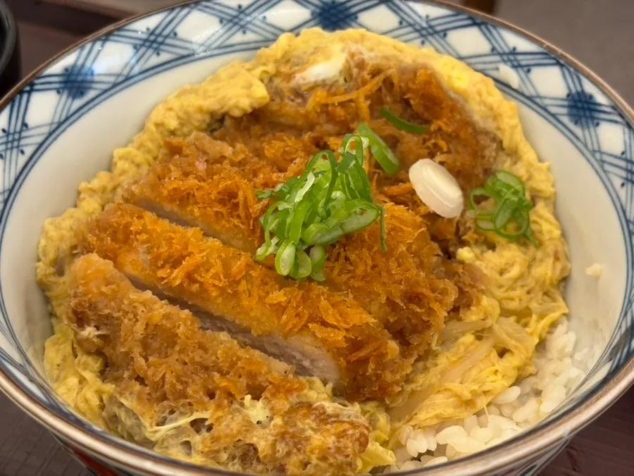 Close-up of katsu don with sauce and rice mixed together