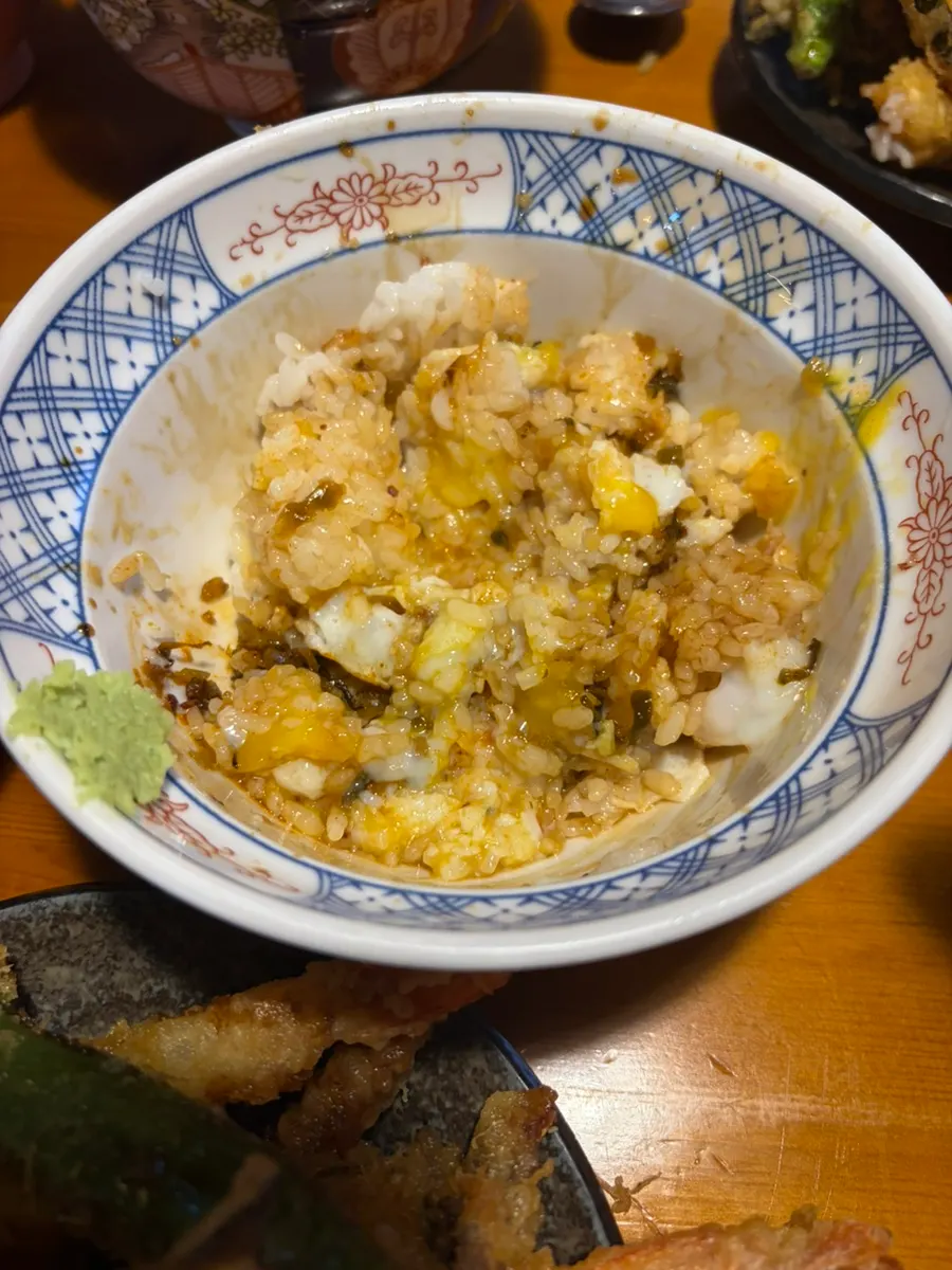A piece of tempura on rice mixed with onsen egg