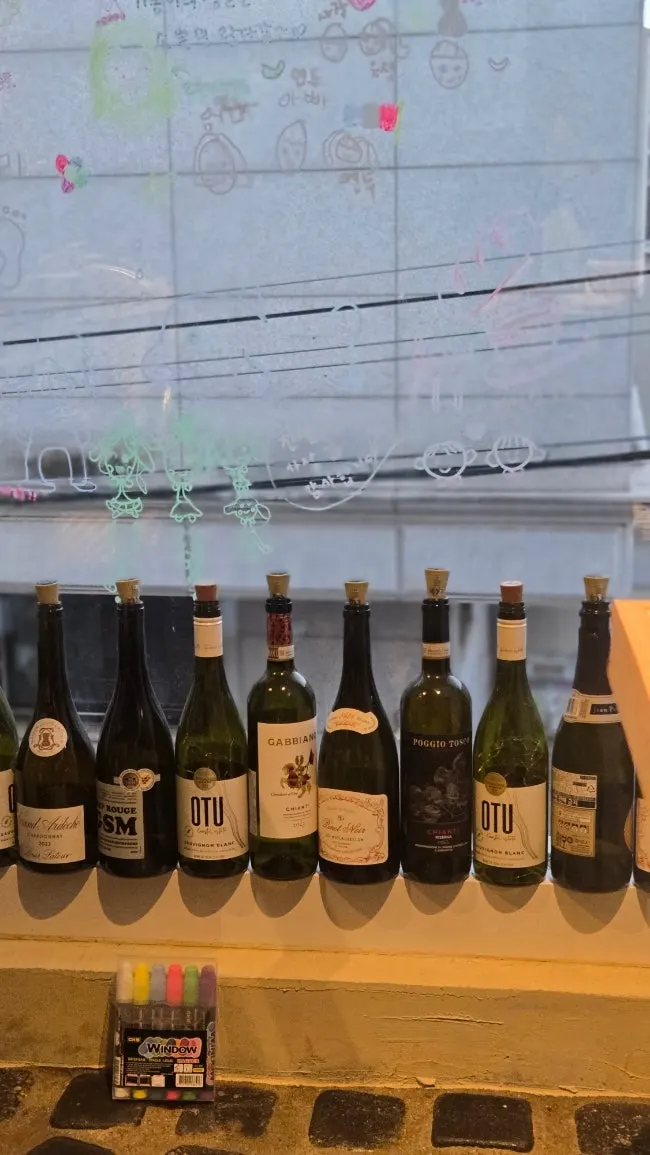 Window with notes left by guests and empty wine bottle decor
