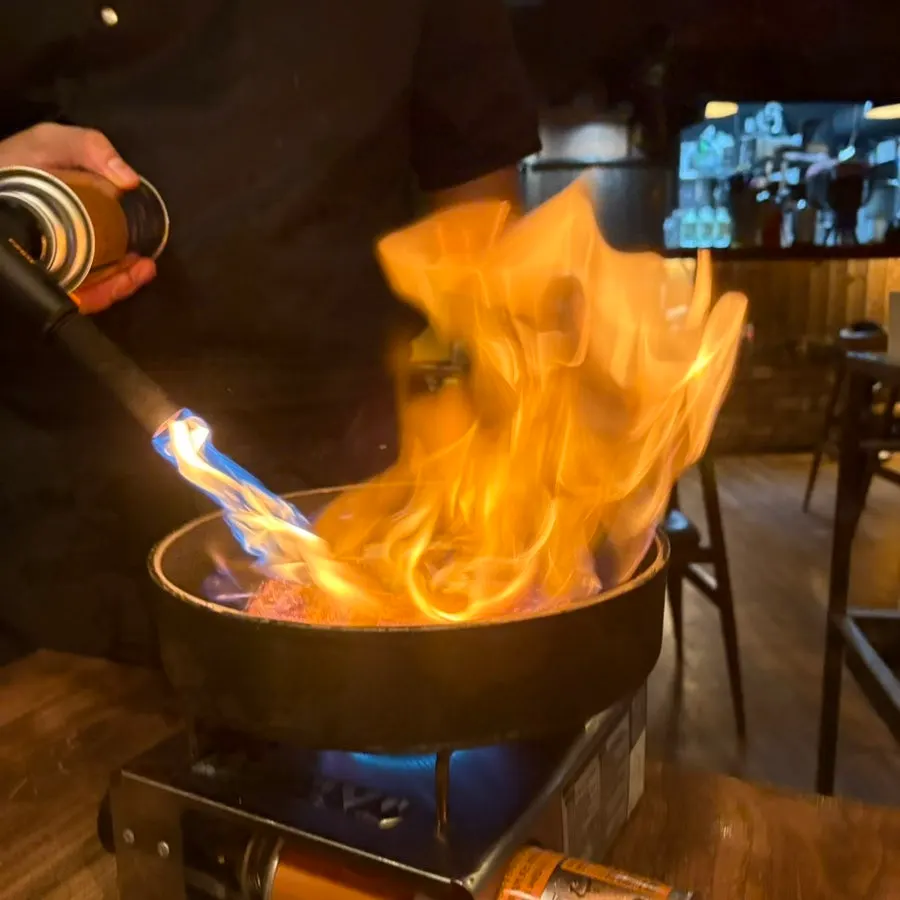 Fire show performance after white wine is poured over the meat
