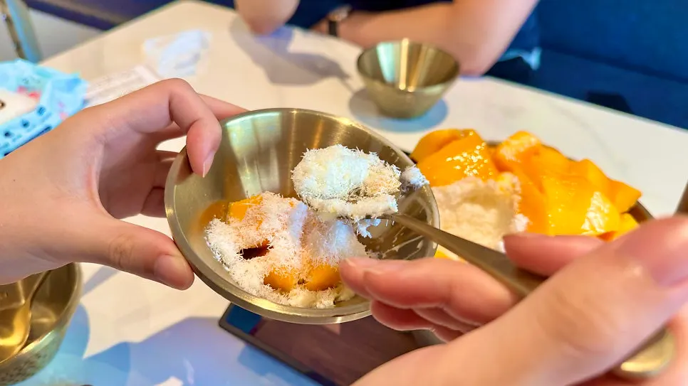 A spoonful of apple mango bingsu being taken