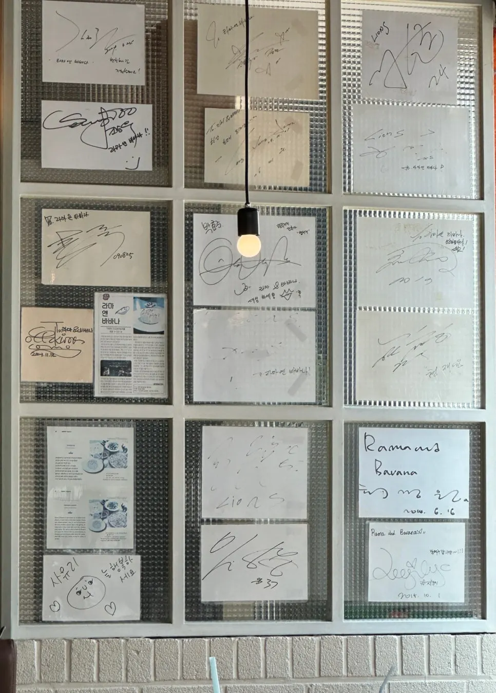 Grid-glass wall covered in celebrity autographs, with the counter behind