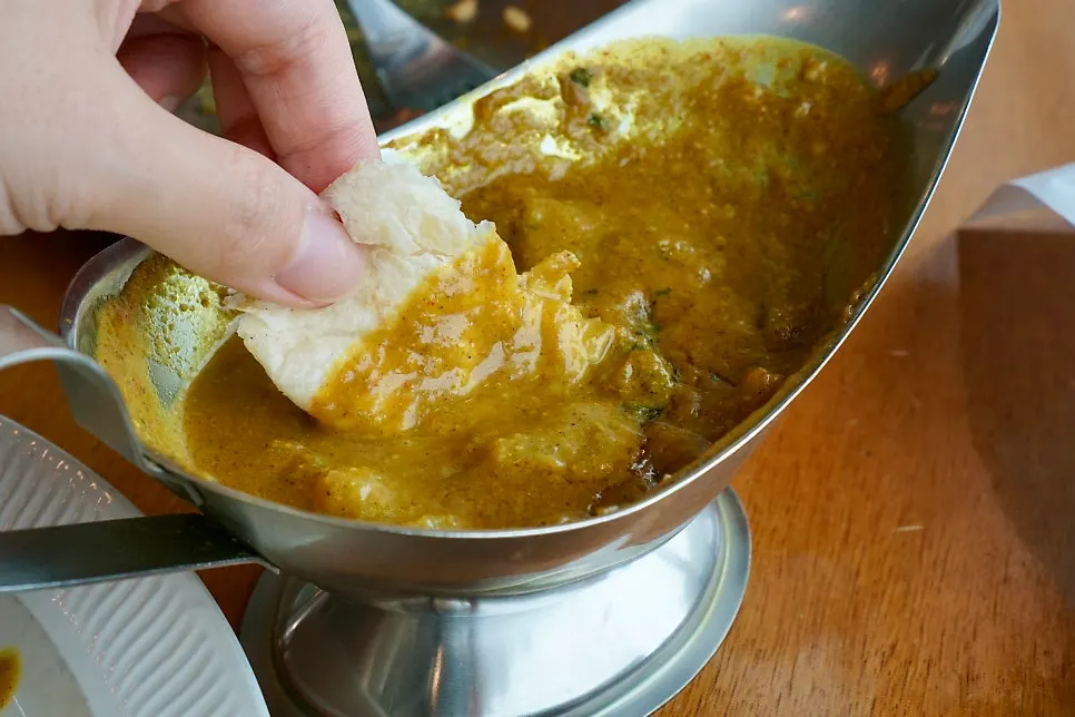 Dipping naan into the beef curry