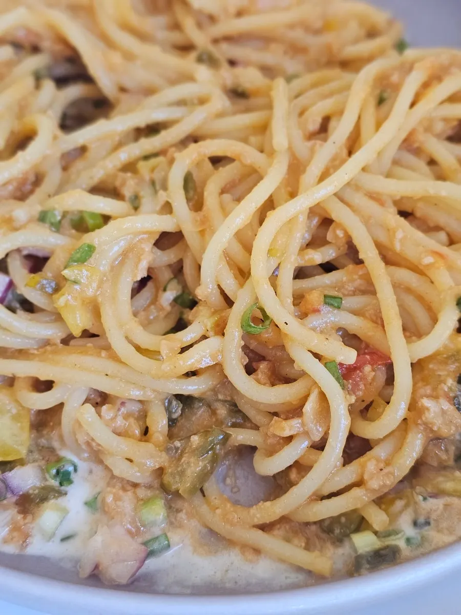 Ragu pasta topped with scallions and bell pepper