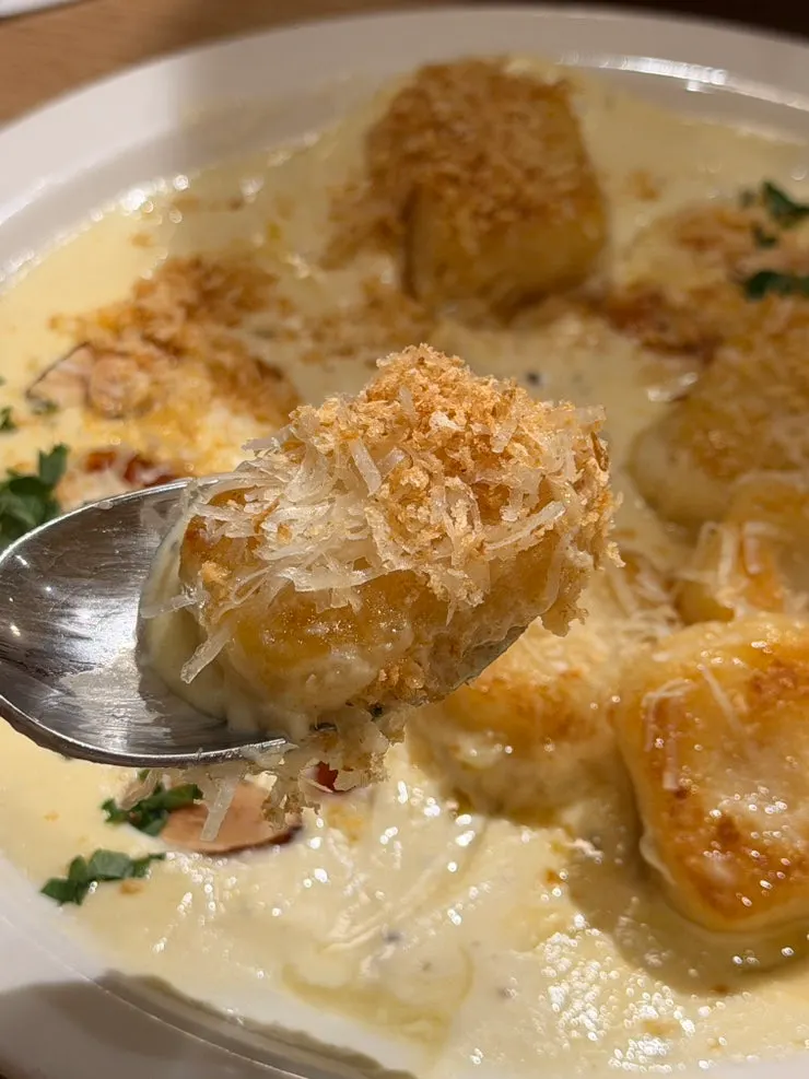 Potato gnocchi with a scoop of cream sauce lifted up