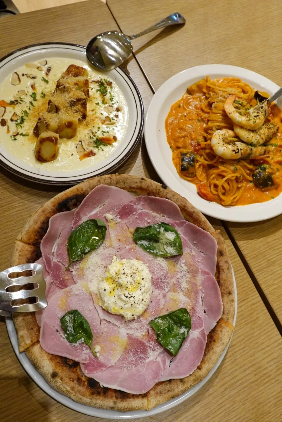 Table setting with pizza, cream gnocchi, and shrimp rosé pasta