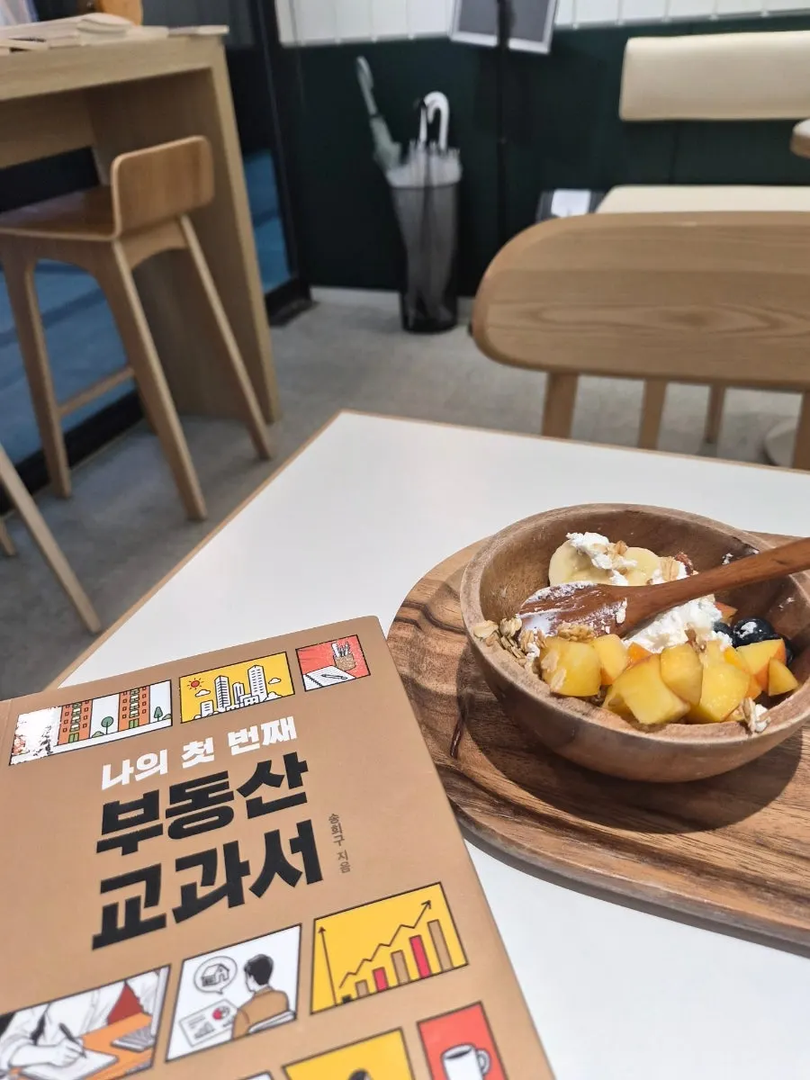 Yogurt bowl and a book on a tray at the window seat