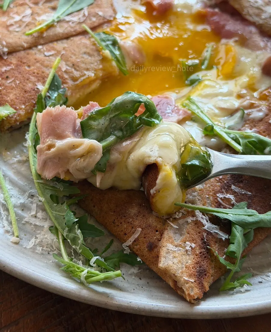 Galette topped with jambon, brie cheese, and arugula