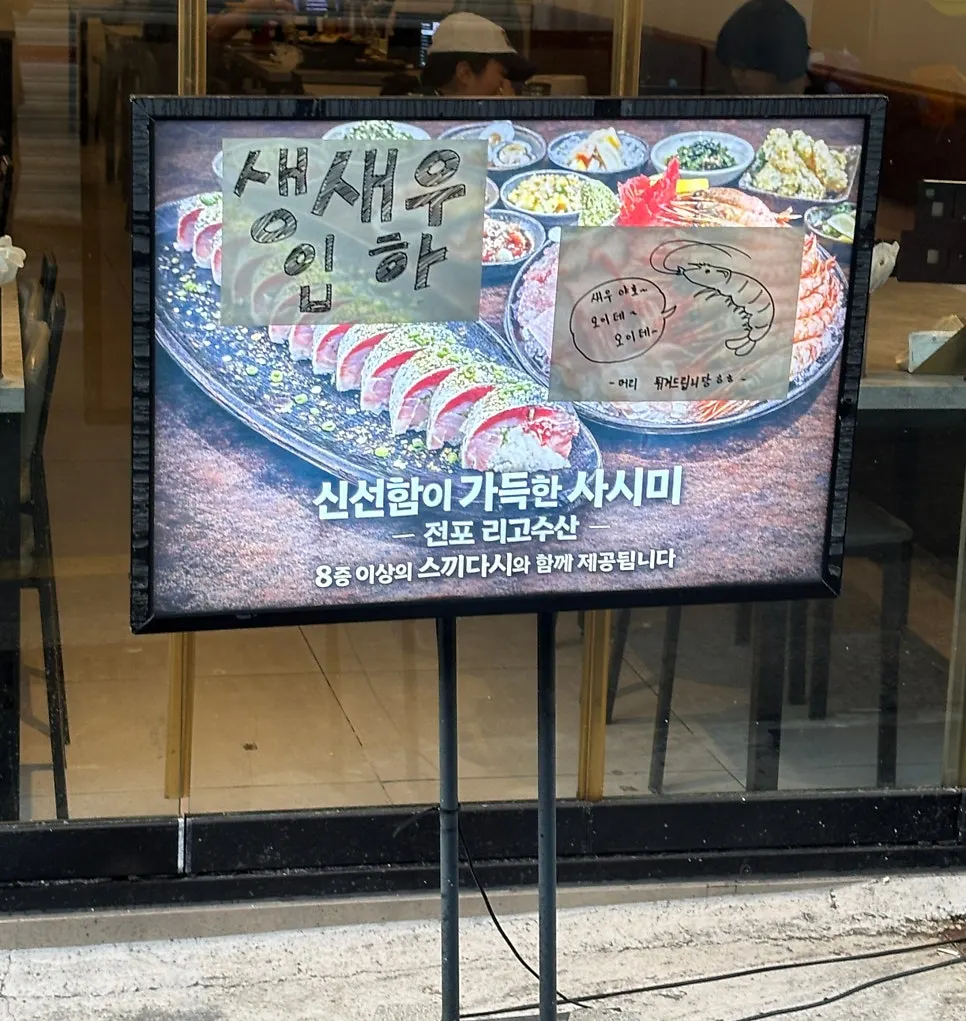 Storefront entrance with a sign announcing fresh live sweet shrimp sashimi