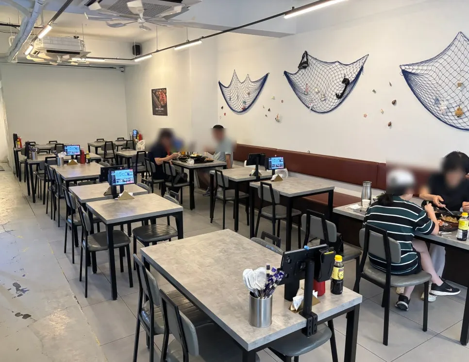 Long dining hall with 4-person tables stretching to the back