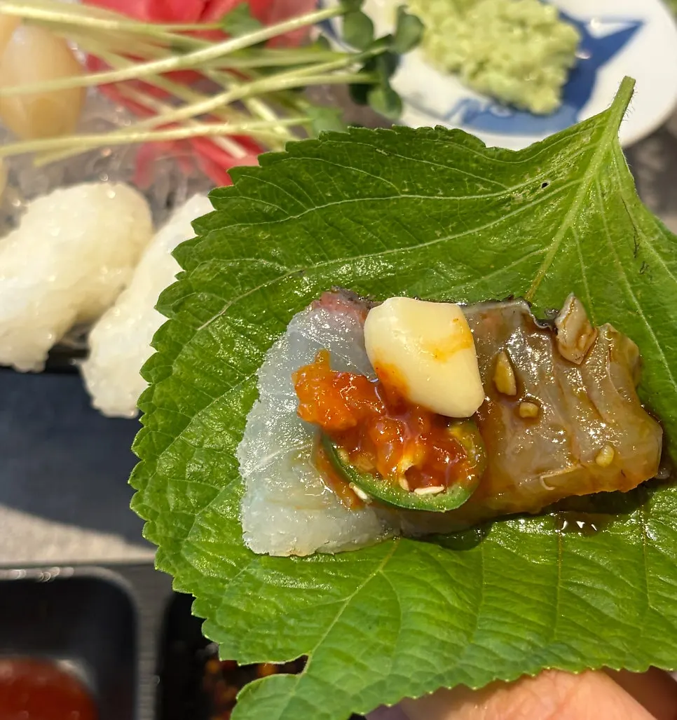 A piece of sweet shrimp sashimi dipped in soy sauce