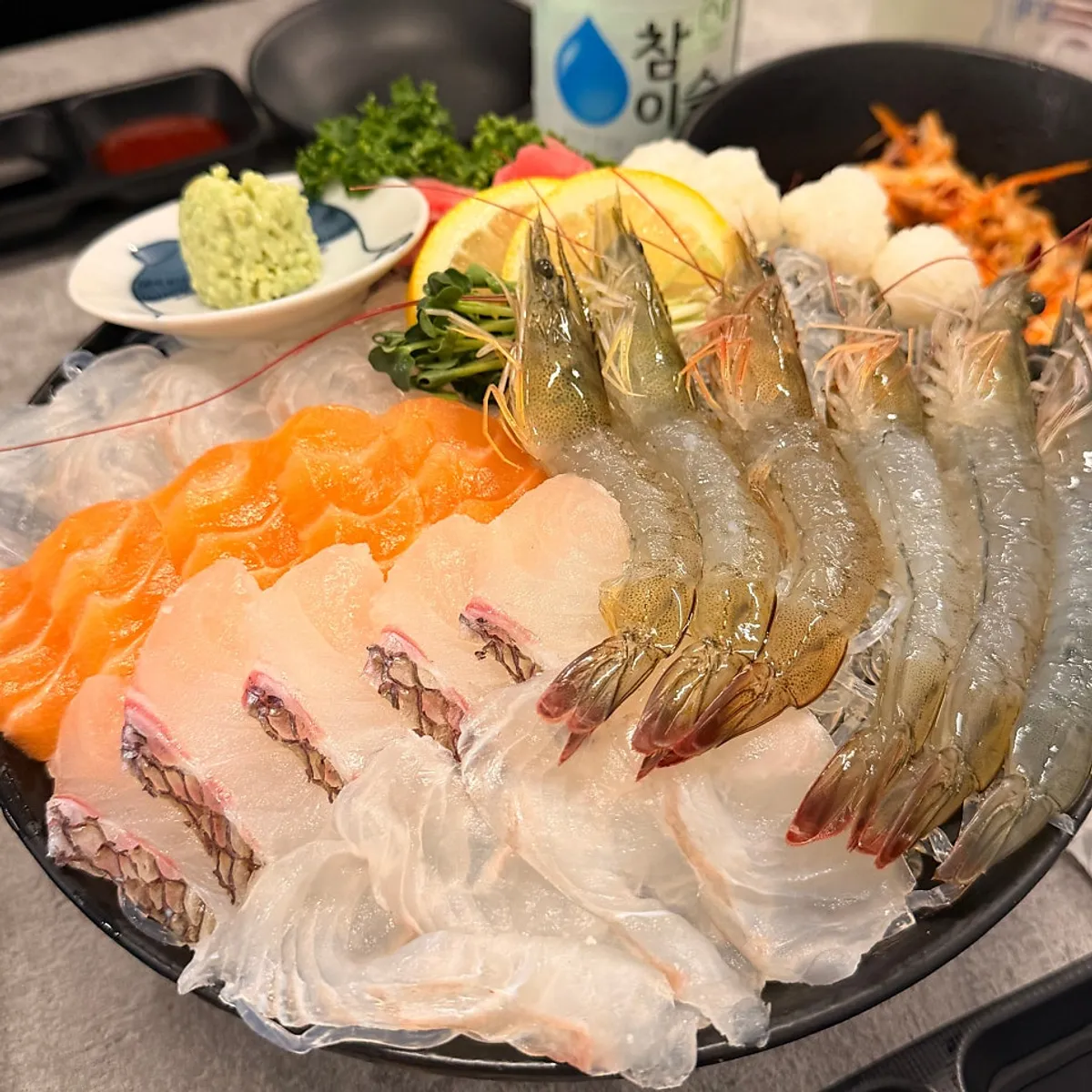 Full table spread with mixed sashimi and raw shrimp platter