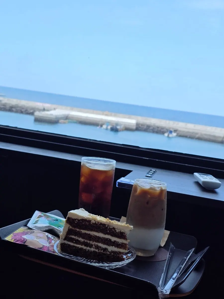 Drinks and cake set against the full-window sea view