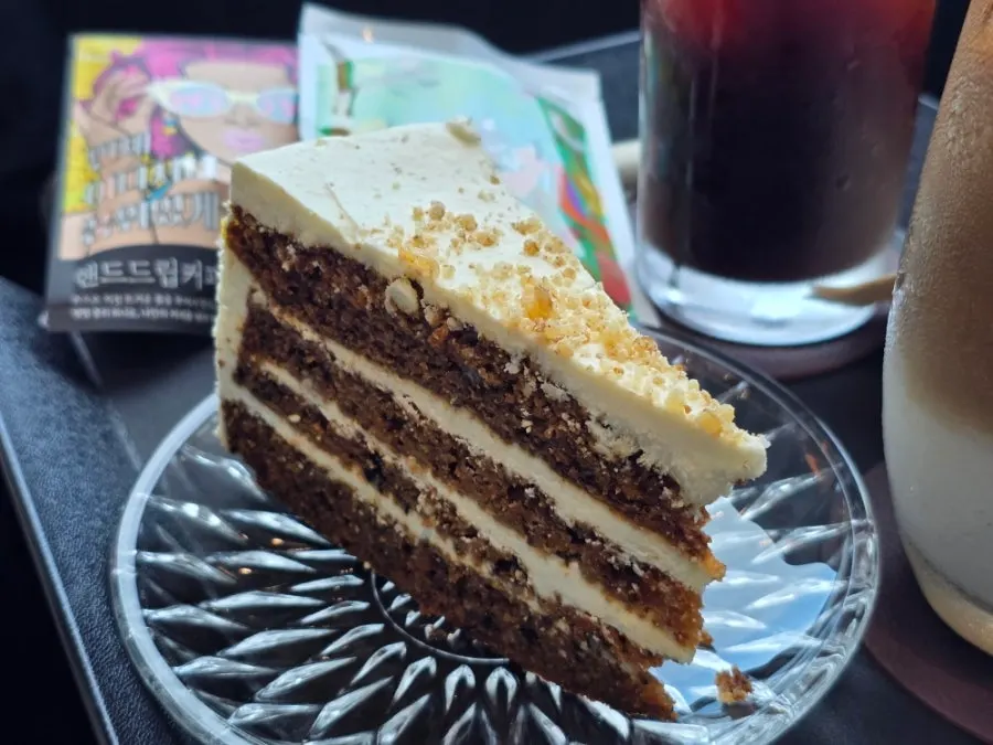 A slice of carrot cake with cream cheese sandwiched between layers