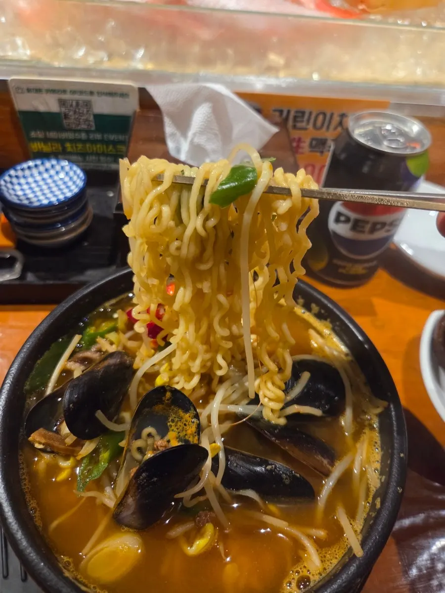 Seafood ramyeon noodles lifted up on chopsticks
