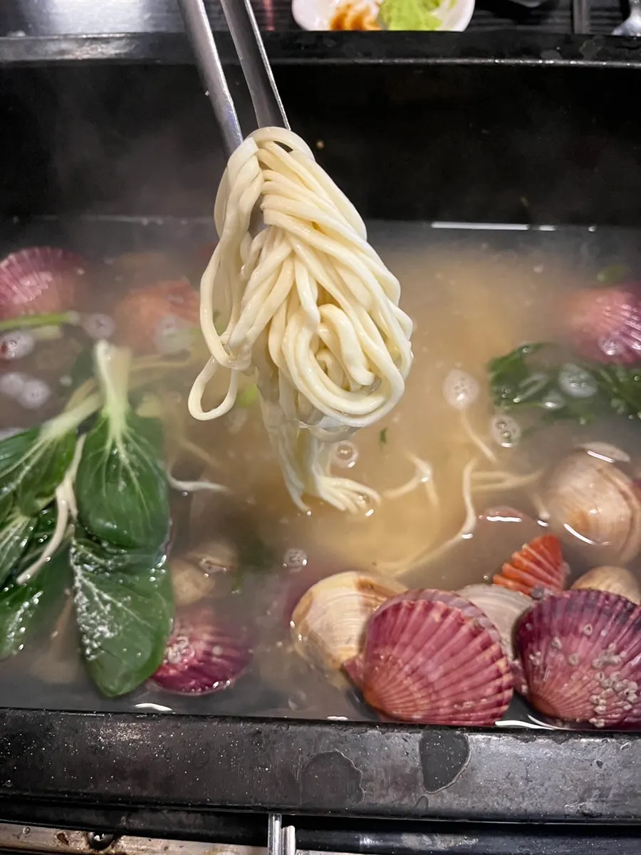 Kalguksu noodles added to the leftover clam broth