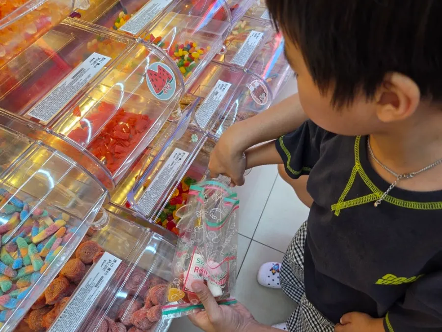 Child filling a bag with jelly alongside a guardian