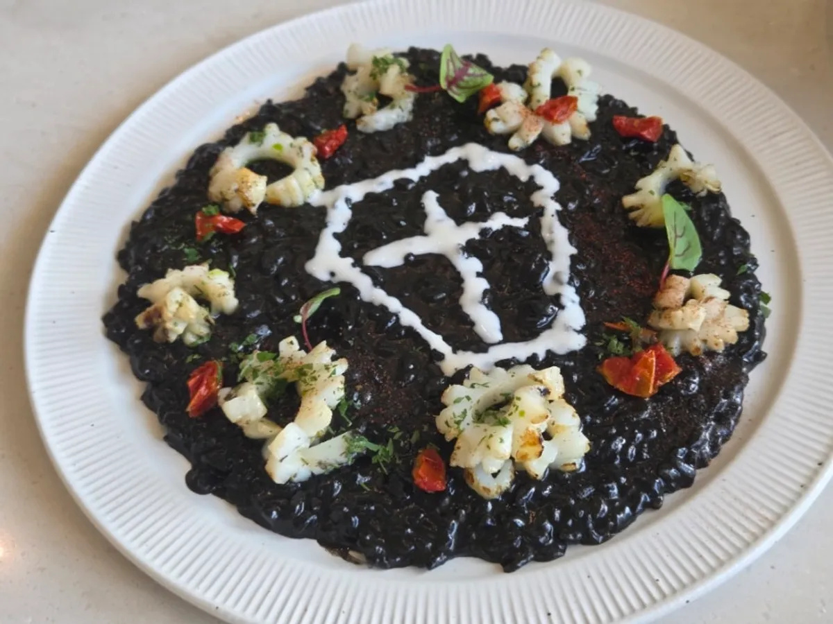 Eclipse squid ink risotto plated in a coffin shape