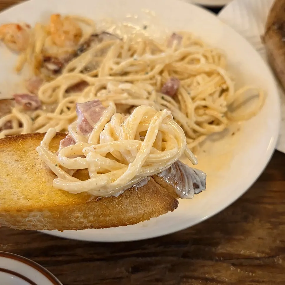 Sliced grilled bacon placed on top of the pasta