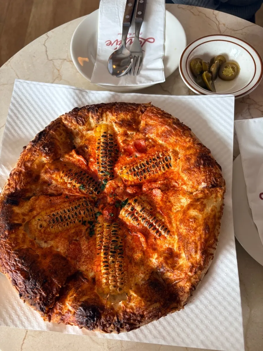A whole corn pizza on the table