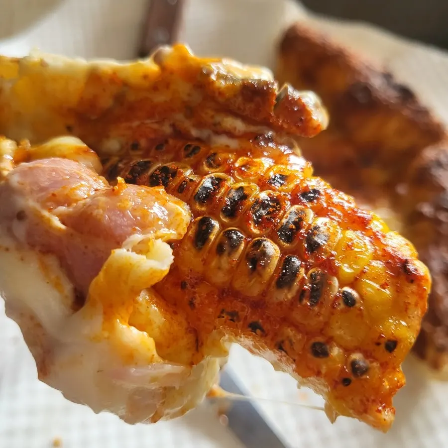Pizza topped with whole corn kernels and bacon