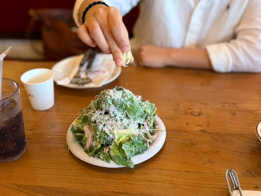 Caesar salad piled up like a mountain with a grilled lemon
