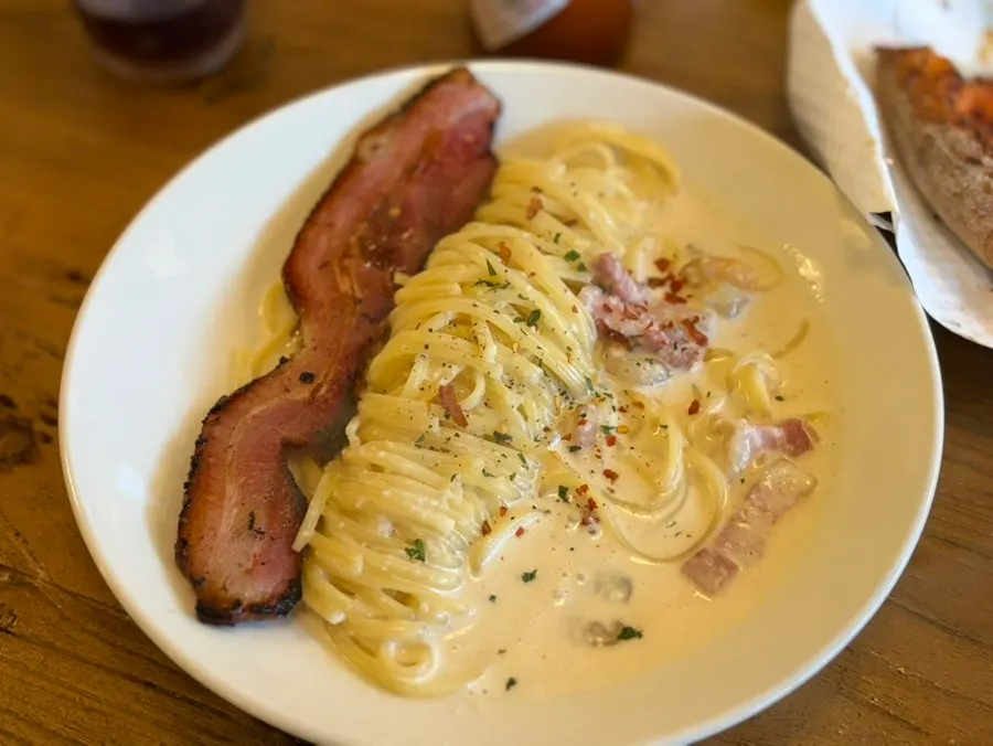 Alfredo cream pasta topped with whole bacon