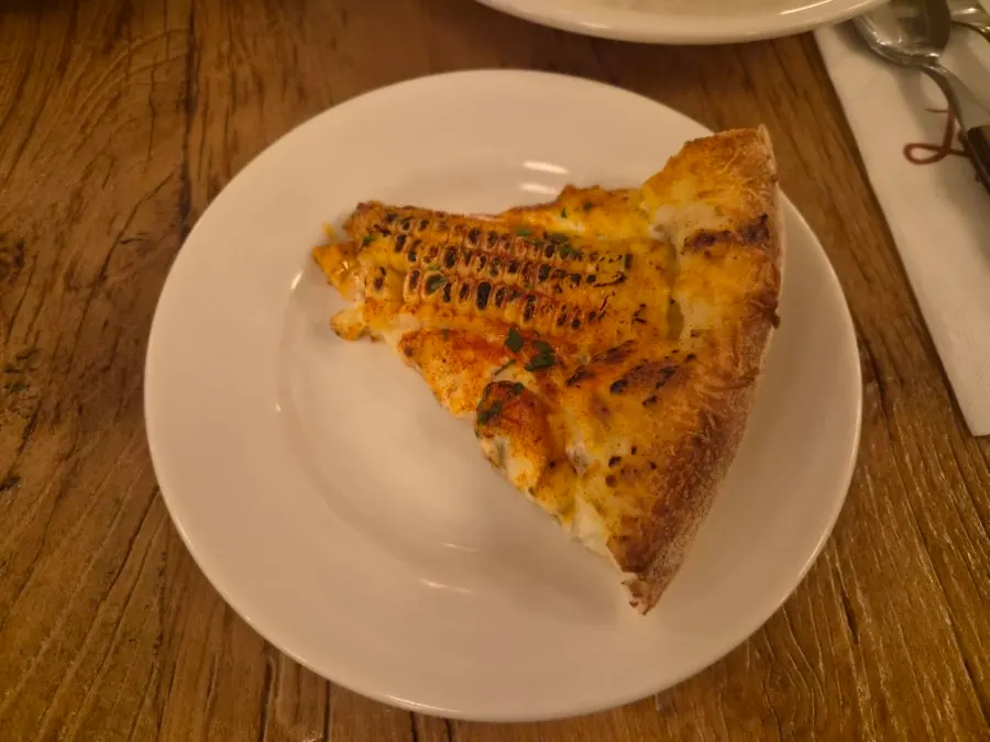 A slice removed from the corn pizza