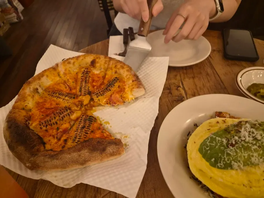 A cheese-stretching slice of corn pizza