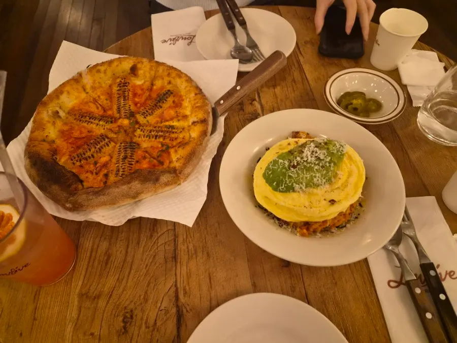 Table with lasagna and corn pizza served together