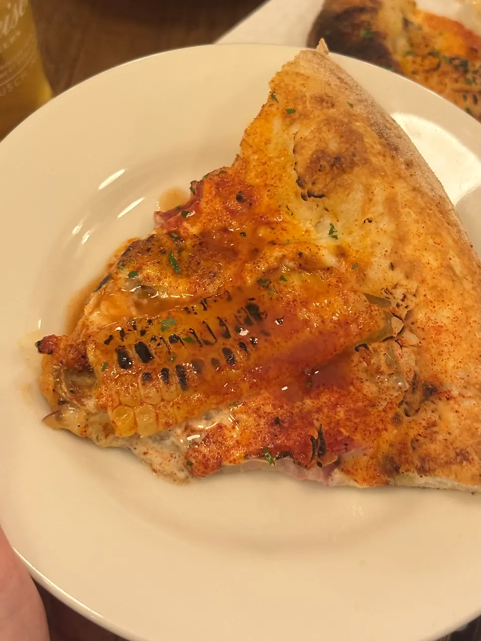 A pizza slice topped with white truffle cream and roasted corn