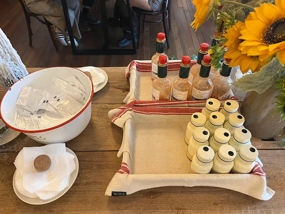 Self-serve bar with hot sauce and parmesan cheese