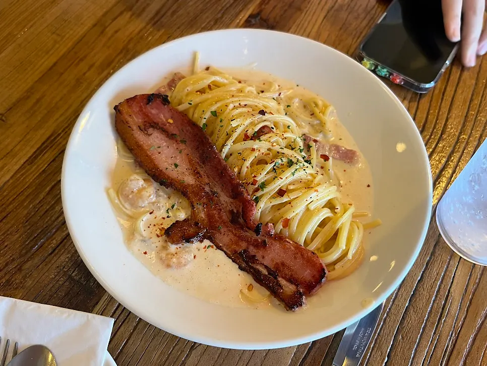 Alfredo cream pasta topped with large bacon