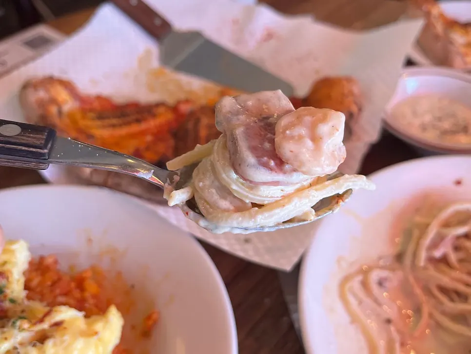 A bite of Alfredo cream pasta with bacon and shrimp