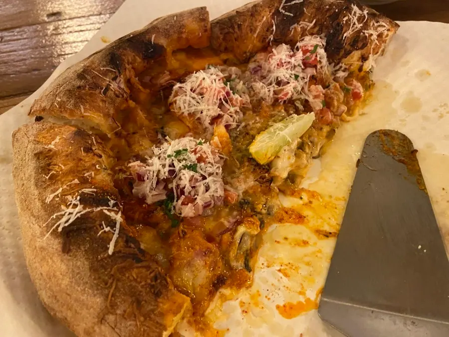 Half of a sweet corn pizza topped generously with corn