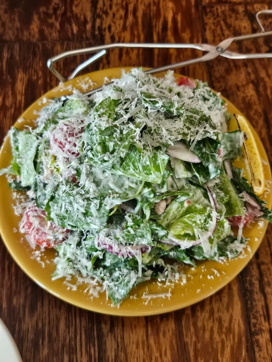 Close-up of Caesar salad topped with arugula and cheese
