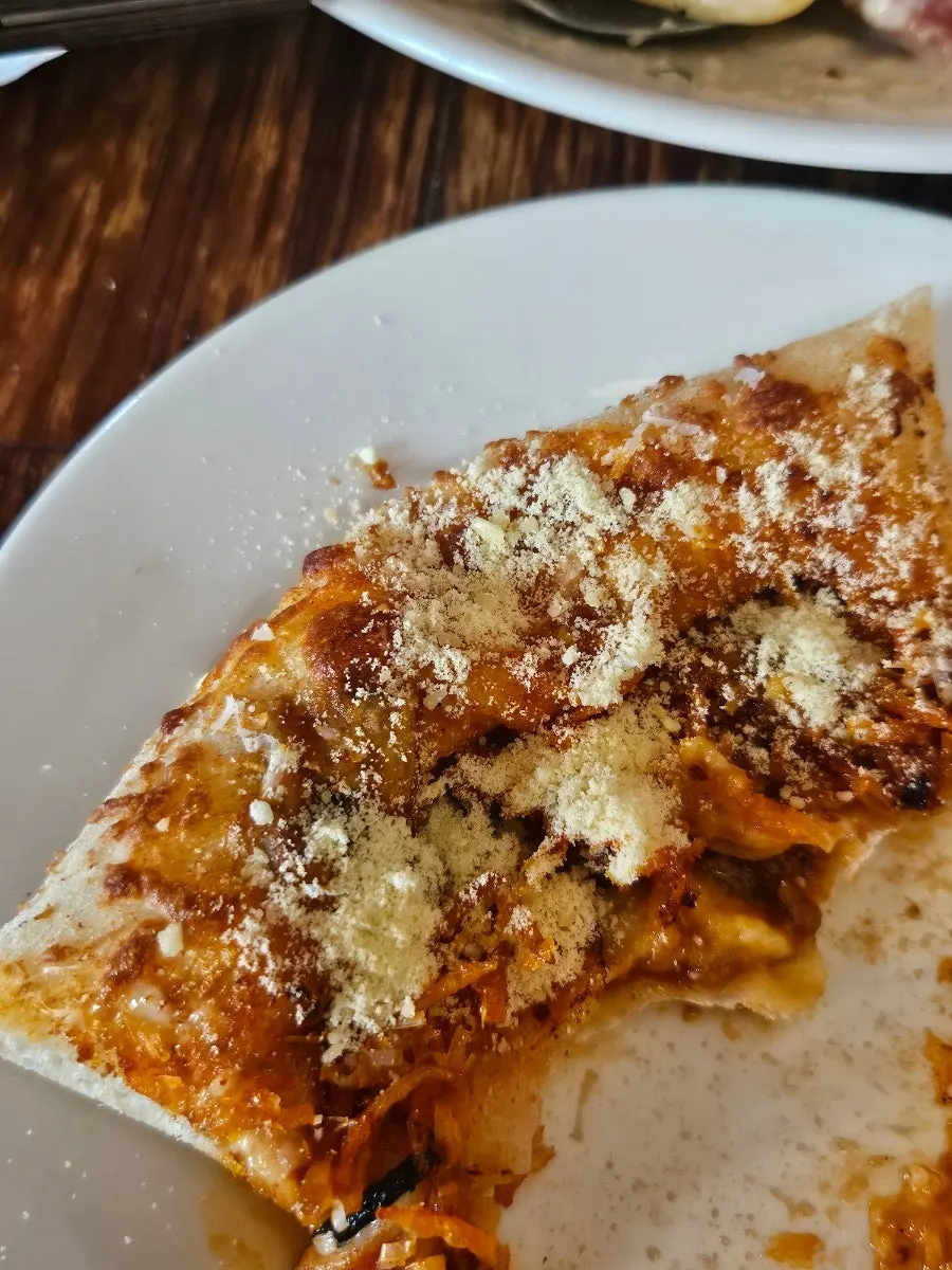 Slice of corn pizza showing the chewy crust end