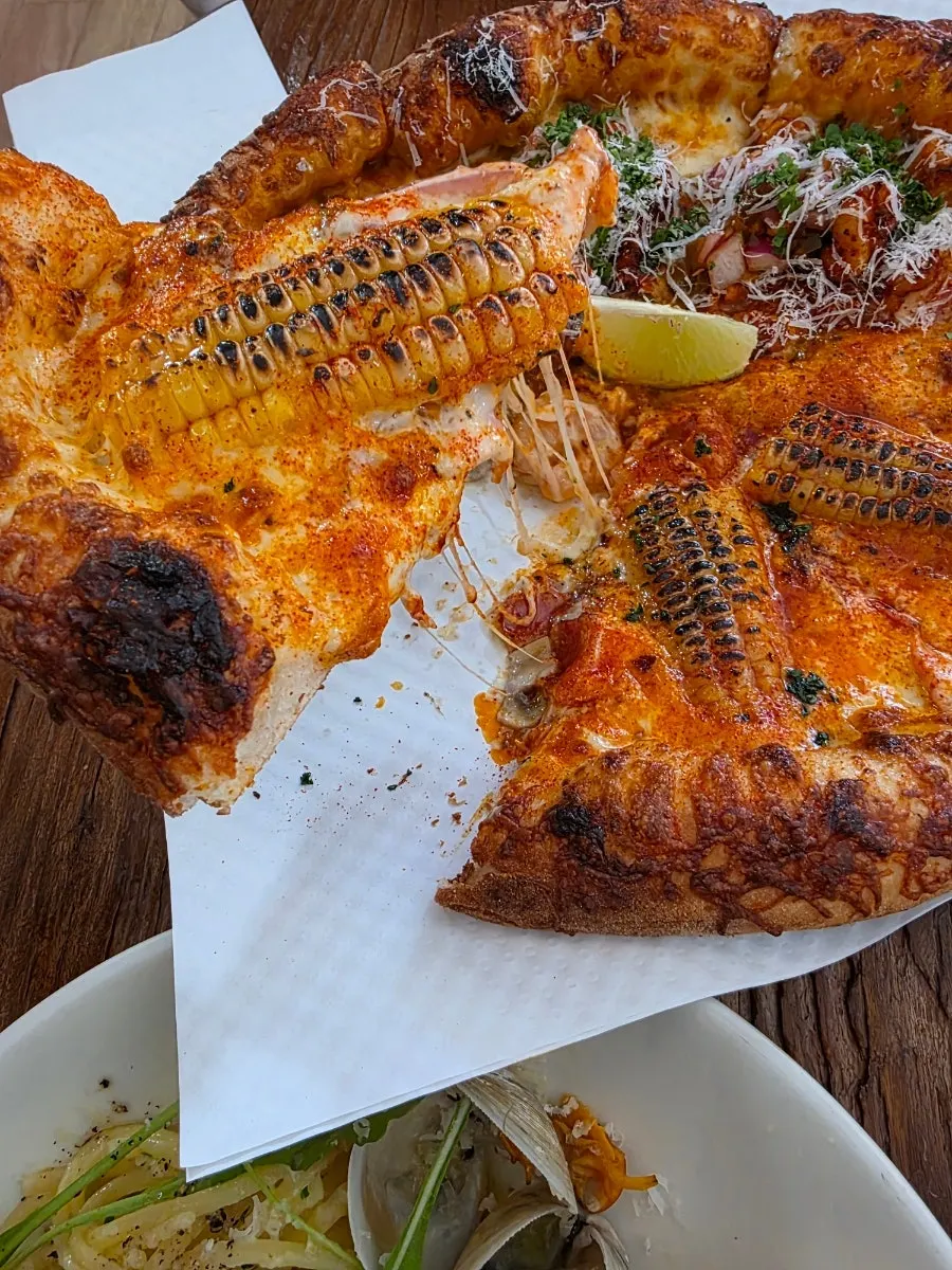A slice of corn pizza topped with large corn kernels