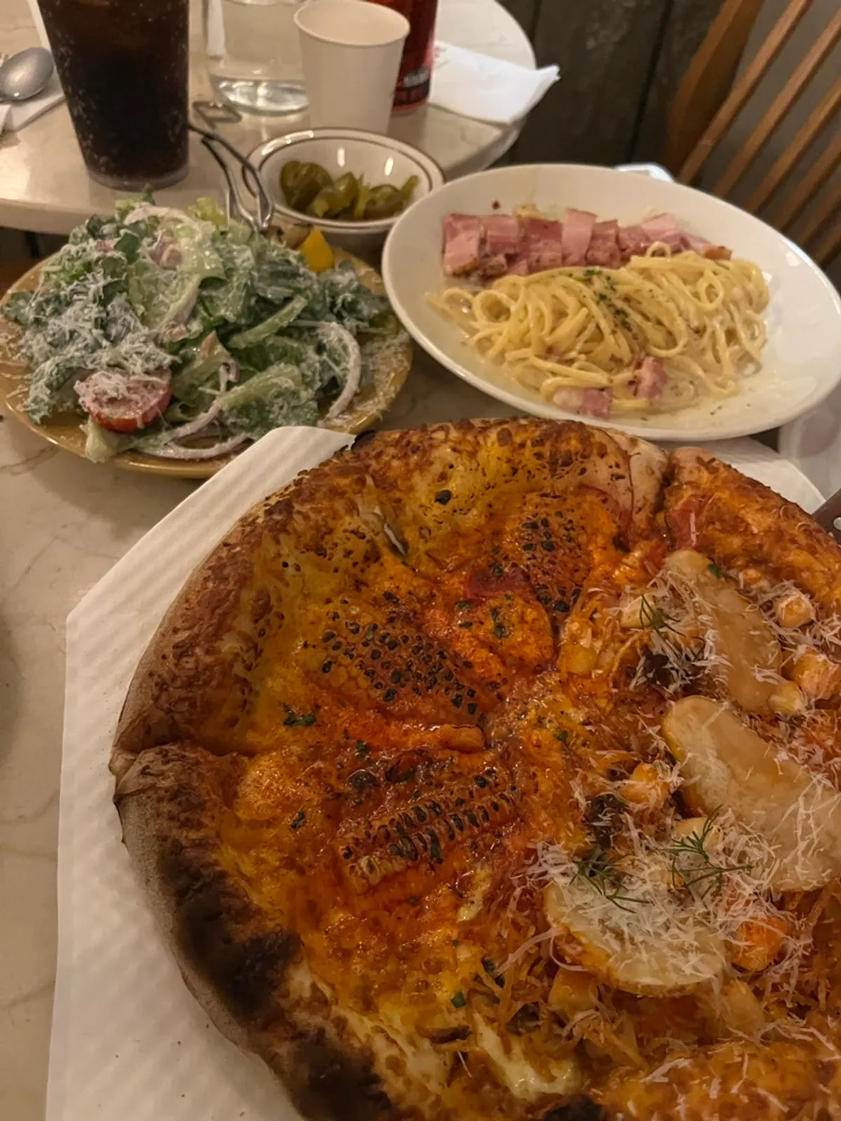 Table with half-and-half pizza, pasta, and salad