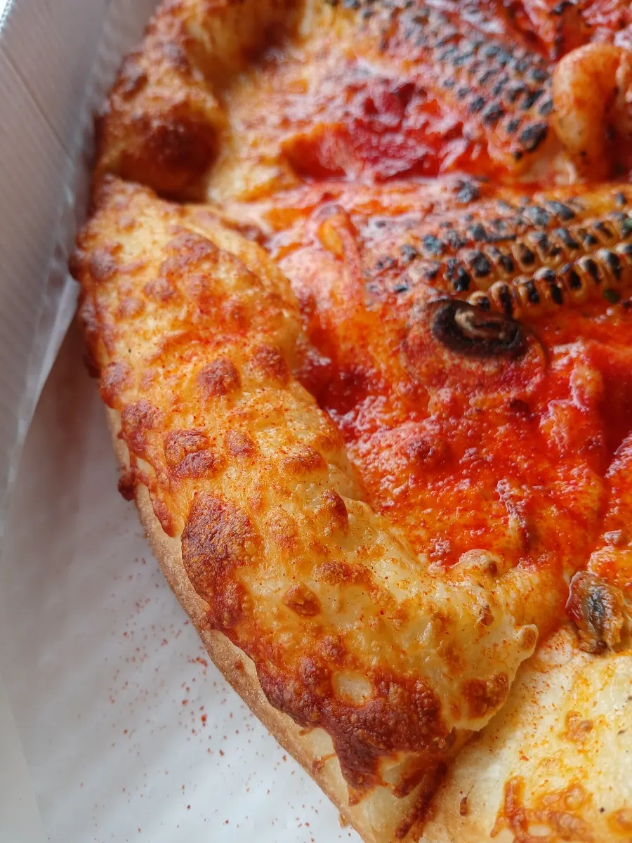Pizza slice topped with shrimp and sweet corn