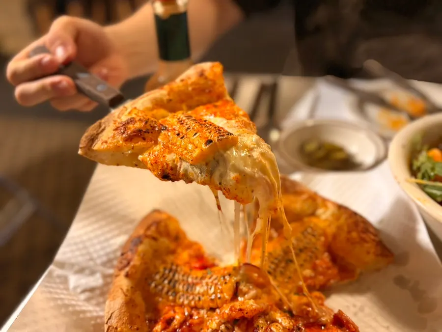 들어 올린 피자 조각에 늘어나는 치즈