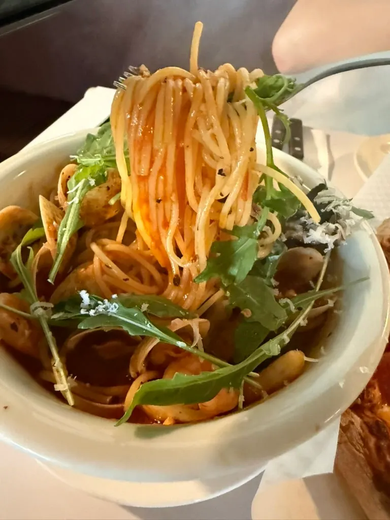 Pasta topped with shrimp, clams, and arugula