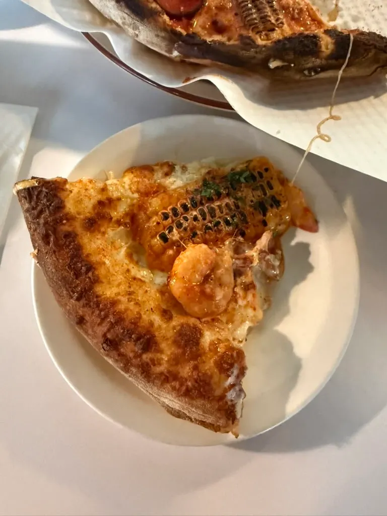 A slice of pizza topped with shrimp and corn